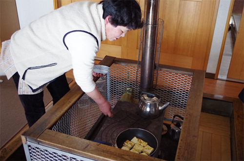 写真1:薪ストーブの上で、手作り豆腐を温める神楽栄子さん