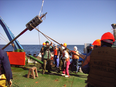 巨大な重りの付いたピストンコアラーで海底堆積物の柱状試料を採取