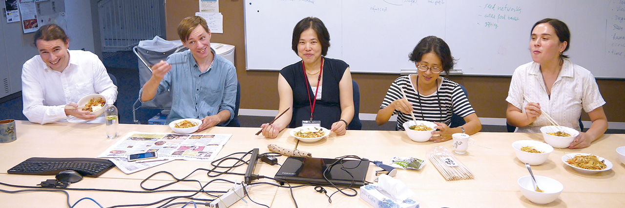 ホワイトボードの前で昼食をとる研究員