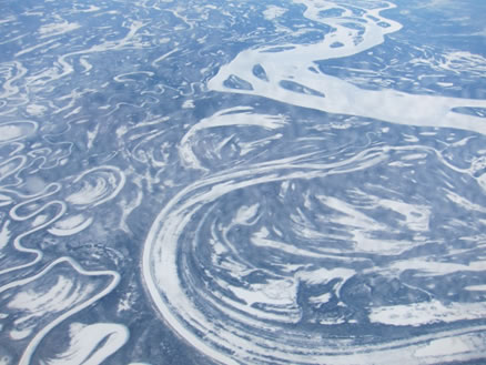 飛行機から見た冬のシベリアの大地。多数の川がうねっている
